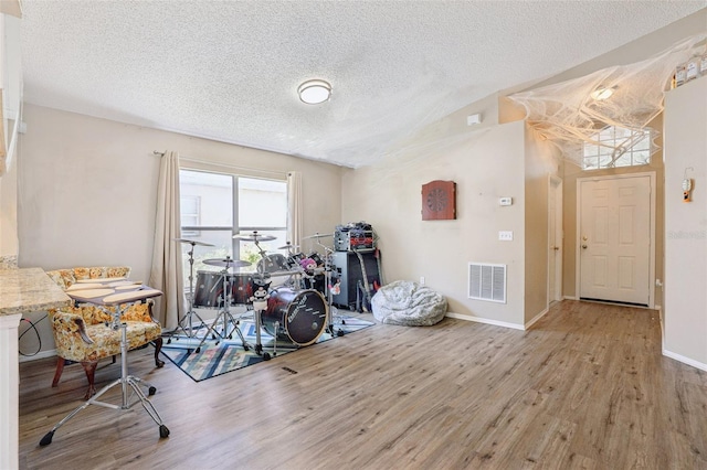 playroom with baseboards, wood finished floors, visible vents, and a textured ceiling