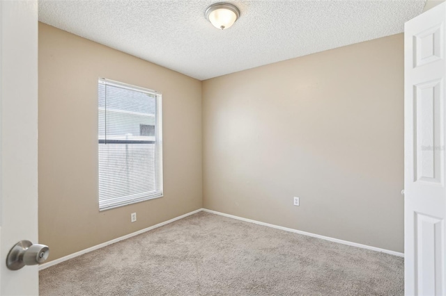 carpeted spare room featuring baseboards and a textured ceiling