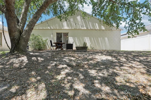 rear view of house featuring fence and concrete block siding