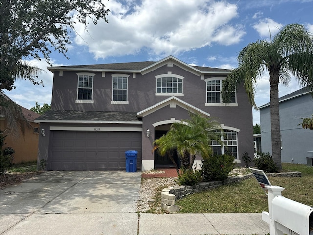traditional-style house with an attached garage, driveway, and stucco siding