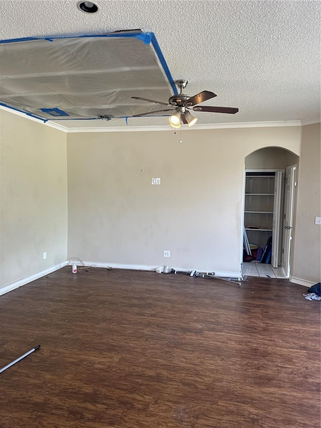 empty room featuring ornamental molding, wood finished floors, baseboards, a textured ceiling, and a ceiling fan