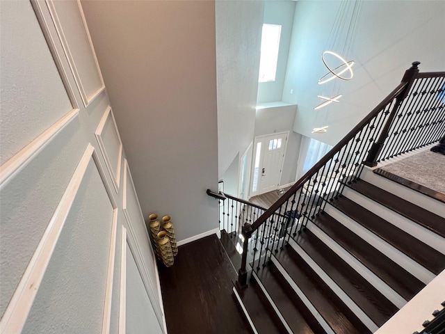 2926 Crest Wave Dr, Clermont, FL 34711 - stairs featuring baseboards, plenty of natural light, a towering ceiling, wood finished floors, and a chandelier