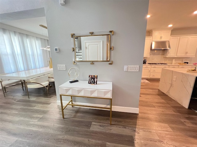 2926 Crest Wave Dr, Clermont, FL 34711 - kitchen with light wood-style flooring, gas stovetop, under cabinet range hood, white cabinetry, and recessed lighting
