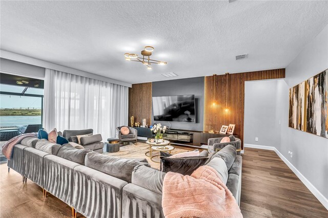 2926 Crest Wave Dr, Clermont, FL 34711 - living room featuring a textured ceiling, wood finished floors, baseboards, and a chandelier