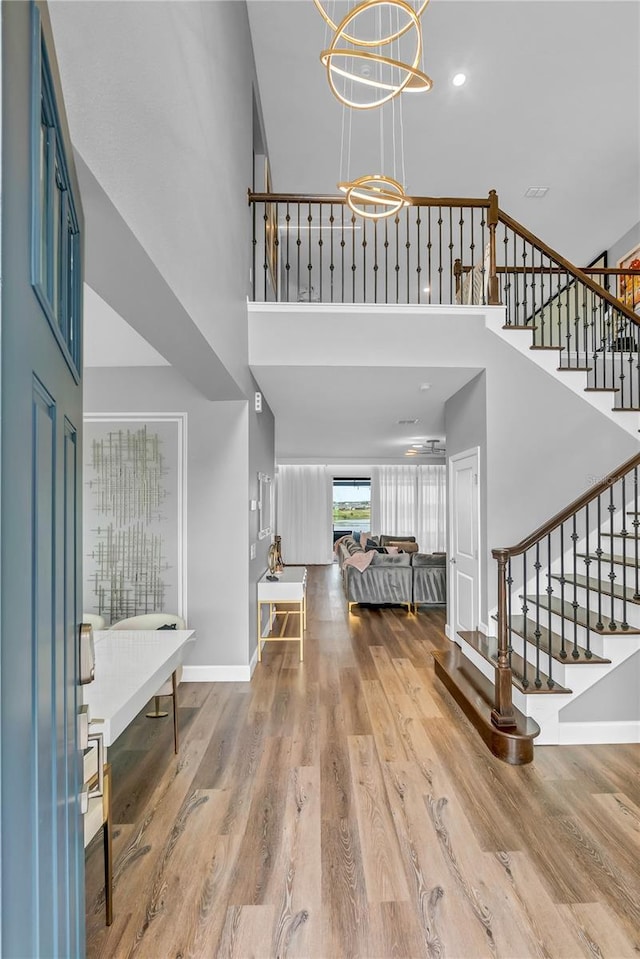 2926 Crest Wave Dr, Clermont, FL 34711 - foyer entrance with a towering ceiling, stairway, a chandelier, wood finished floors, and baseboards