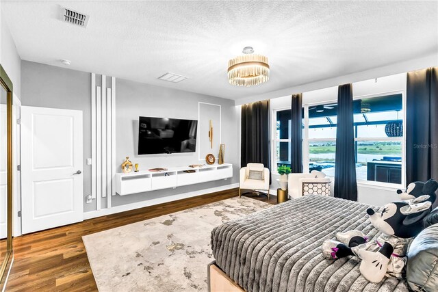 2926 Crest Wave Dr, Clermont, FL 34711 - bedroom featuring wood finished floors, a textured ceiling, a chandelier, and baseboards