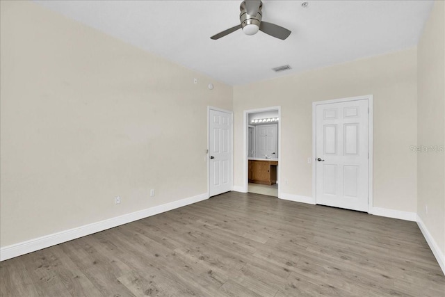 13500 Turtle Marsh Loop Unit 834, Orlando, FL 32837 - unfurnished bedroom featuring ensuite bathroom, visible vents, baseboards, a ceiling fan, and wood finished floors