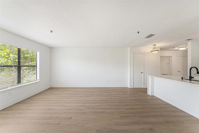11901 4th St N Unit 2107, Saint Petersburg, FL 33716 - unfurnished living room featuring light wood-style flooring, baseboards, a textured ceiling, and a sink
