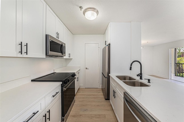 11901 4th St N Unit 2107, Saint Petersburg, FL 33716 - kitchen featuring stainless steel appliances, a sink, light wood-type flooring, white cabinetry, and a textured ceiling