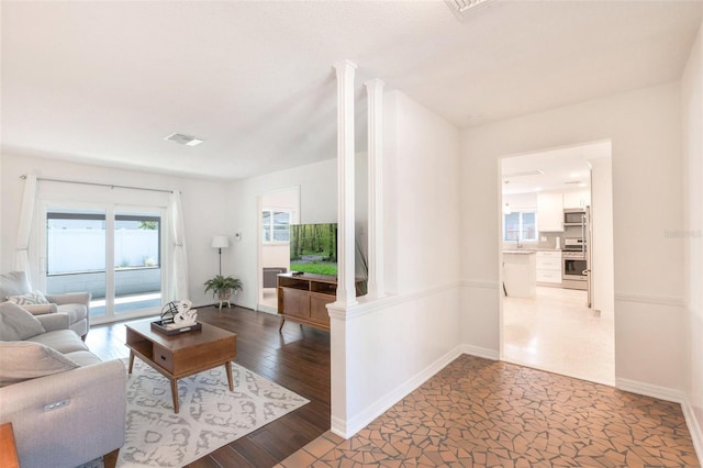 living area with baseboards, visible vents, and wood finished floors