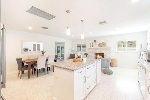 kitchen with a fireplace, visible vents, decorative light fixtures, and baseboards