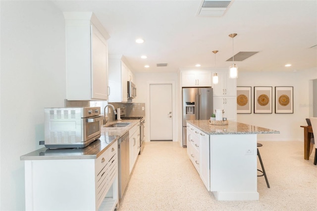kitchen featuring stainless steel appliances, a sink, white cabinetry, a center island, and a kitchen breakfast bar