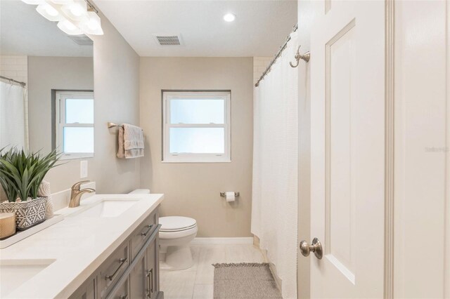bathroom featuring a sink, double vanity, visible vents, toilet, and tile patterned floors