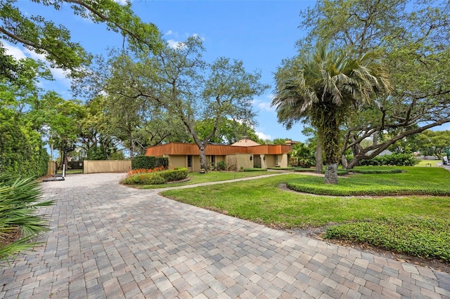 ranch-style home featuring fence, a front lawn, and decorative driveway