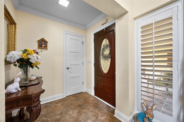 foyer entrance with stone finish floor, a wealth of natural light, baseboards, and ornamental molding