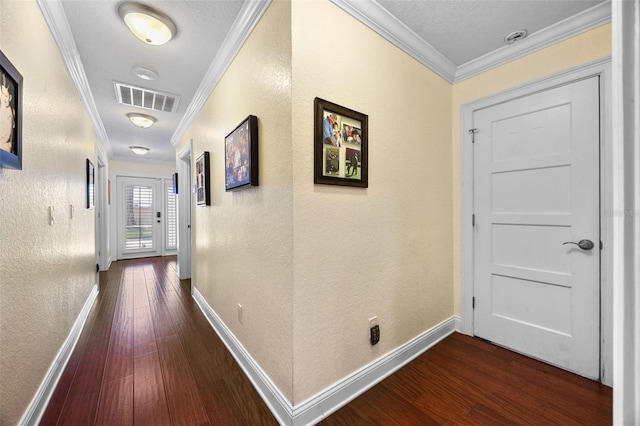 hall featuring baseboards, visible vents, dark wood-type flooring, and ornamental molding