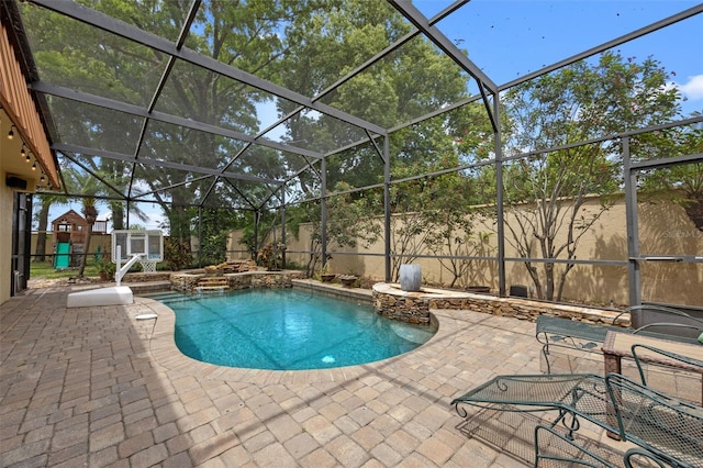 view of pool with glass enclosure, a fenced in pool, a patio area, and an in ground hot tub