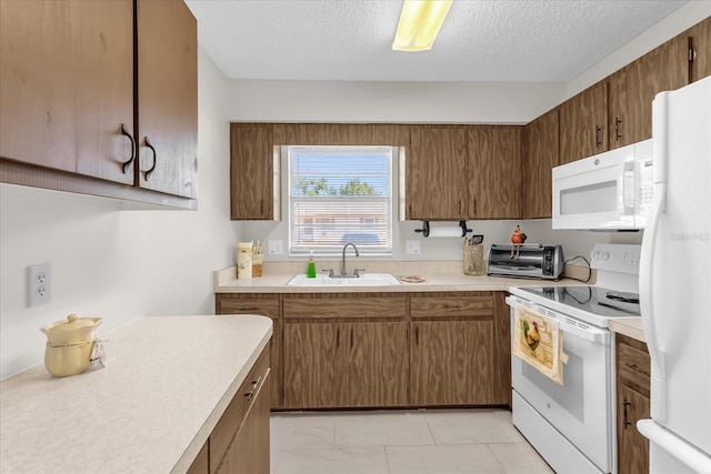 kitchen featuring a toaster, a sink, a textured ceiling, white appliances, and light countertops
