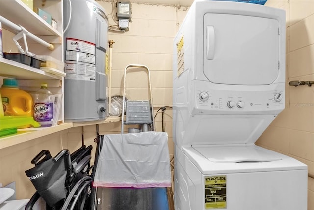 washroom with water heater, stacked washing maching and dryer, and laundry area