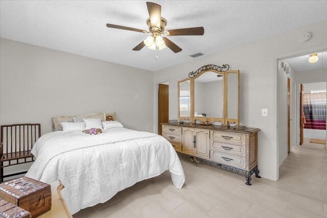 bedroom with light tile patterned flooring, a textured ceiling, visible vents, and a ceiling fan