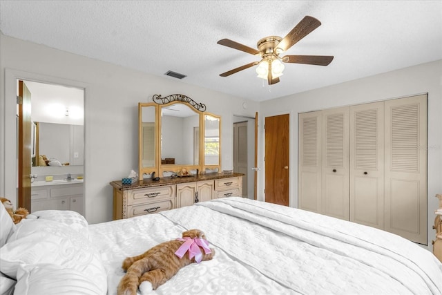 bedroom with two closets, visible vents, a ceiling fan, and ensuite bathroom