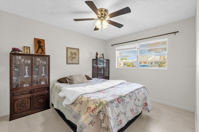 bedroom featuring a textured ceiling, tile patterned flooring, baseboards, and ceiling fan