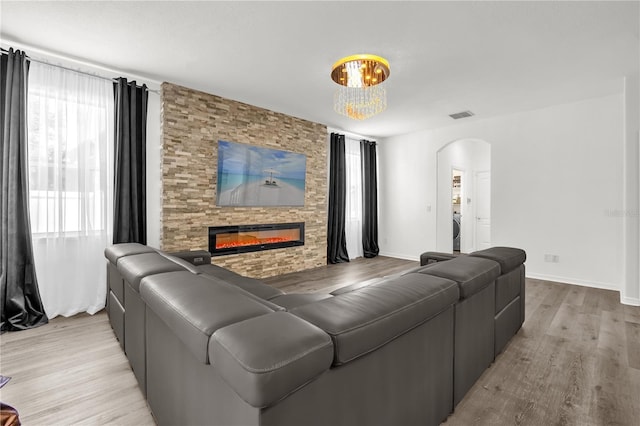1114 Landale Ct, Orlando, FL 32828 - living room featuring arched walkways, light wood finished floors, a fireplace, and a chandelier