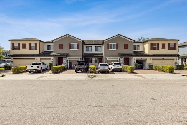 multi unit property featuring stucco siding, driveway, and a garage