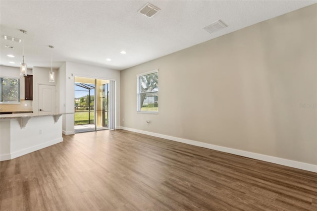 unfurnished living room featuring baseboards, wood finished floors, visible vents, and recessed lighting