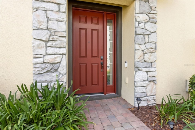 property entrance featuring stone siding and stucco siding