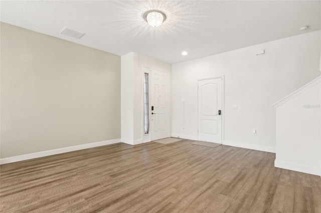 spare room with recessed lighting, wood finished floors, visible vents, baseboards, and a textured ceiling
