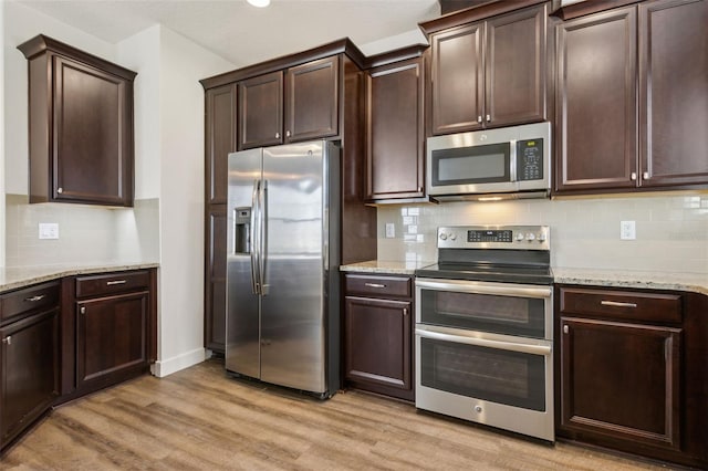 kitchen with light wood-style floors, dark brown cabinetry, backsplash, appliances with stainless steel finishes, and light stone countertops