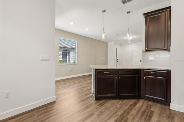 kitchen with wood finished floors, decorative light fixtures, baseboards, dark brown cabinetry, and a peninsula