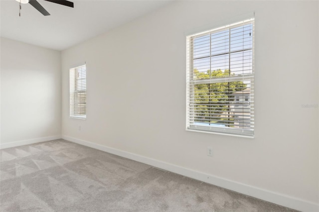 spare room featuring light carpet, baseboards, and ceiling fan
