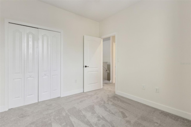 unfurnished bedroom featuring baseboards, carpet flooring, and a closet