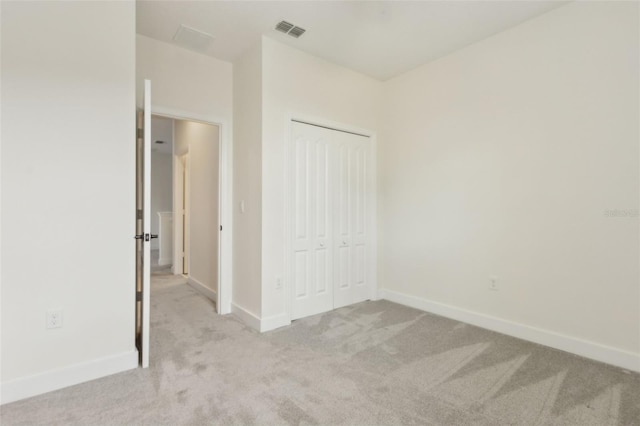 unfurnished bedroom featuring baseboards, carpet floors, visible vents, and a closet