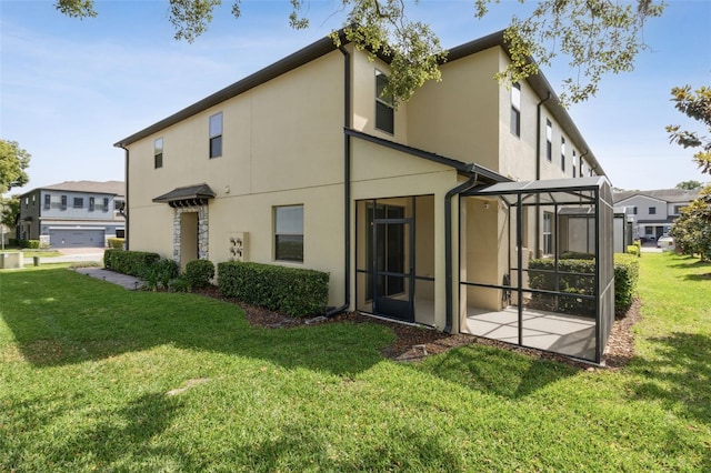 rear view of property featuring a patio, glass enclosure, a yard, and stucco siding