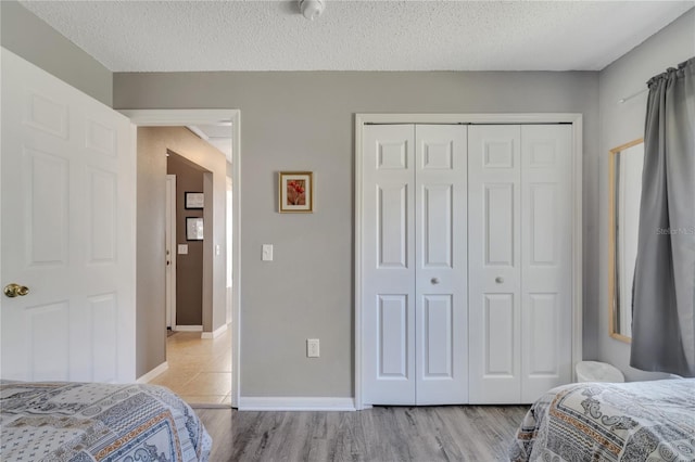 166 Laurel Ridge Pass, Davenport, FL 33897 - bedroom featuring baseboards, light wood-style flooring, a textured ceiling, and a closet