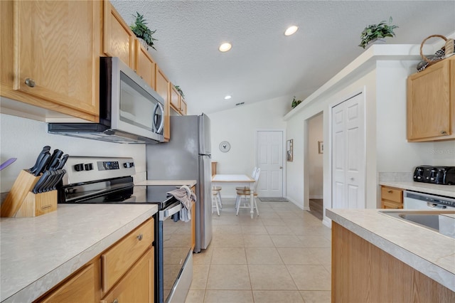 166 Laurel Ridge Pass, Davenport, FL 33897 - kitchen featuring light tile patterned floors, appliances with stainless steel finishes, light brown cabinets, light countertops, and vaulted ceiling