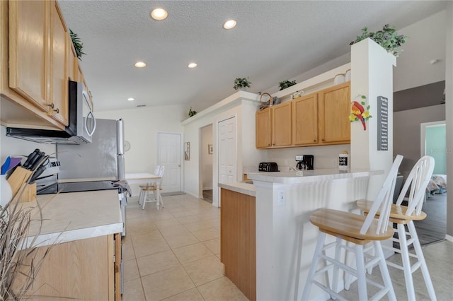 166 Laurel Ridge Pass, Davenport, FL 33897 - kitchen featuring recessed lighting, light brown cabinets, a breakfast bar area, light countertops, and a textured ceiling