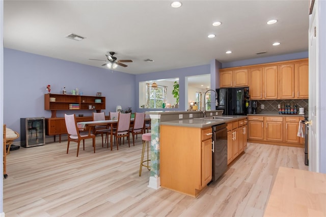 690 Cascading Creek Ln, Winter Garden, FL 34787 - kitchen with visible vents, a sink, black appliances, light wood finished floors, and an island with sink