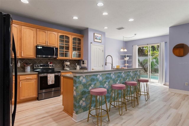 690 Cascading Creek Ln, Winter Garden, FL 34787 - kitchen featuring backsplash, visible vents, a breakfast bar, stainless steel appliances, and light wood-style flooring
