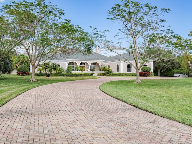 2266 12th St, Vero Beach, FL 32960 - ranch-style home with a front lawn, a chimney, curved driveway, and stucco siding