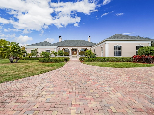 2266 12th St, Vero Beach, FL 32960 - view of front of home with stucco siding, a front lawn, decorative driveway, and a chimney