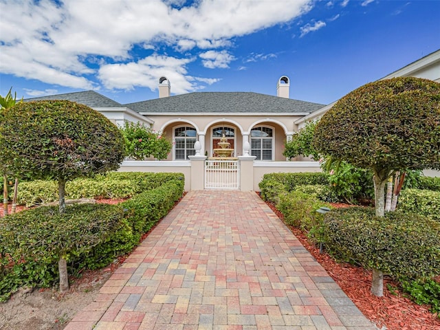 2266 12th St, Vero Beach, FL 32960 - view of front of home with a gate, a fenced front yard, a chimney, a shingled roof, and stucco siding