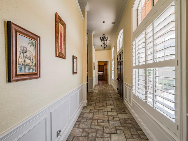 2266 12th St, Vero Beach, FL 32960 - hall featuring brick floor, a wealth of natural light, ornamental molding, and an inviting chandelier