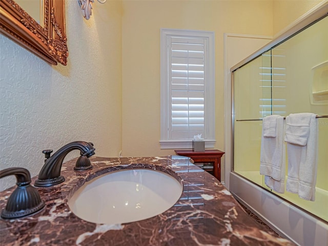 2266 12th St, Vero Beach, FL 32960 - bathroom with a textured wall, a sink, and bath / shower combo with glass door
