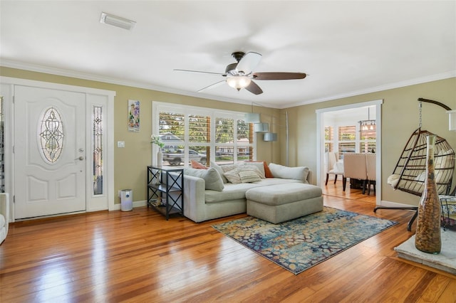 living area with baseboards, visible vents, ceiling fan, ornamental molding, and wood-type flooring