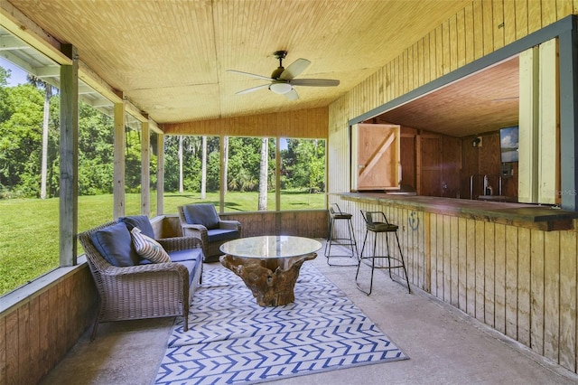 sunroom / solarium with a ceiling fan and exterior bar