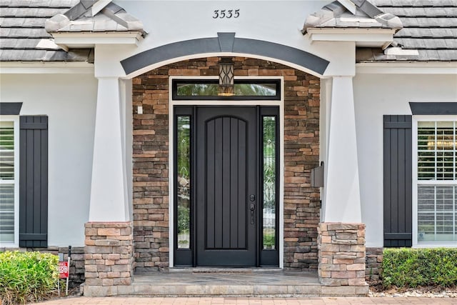 entrance to property featuring stucco siding and stone siding